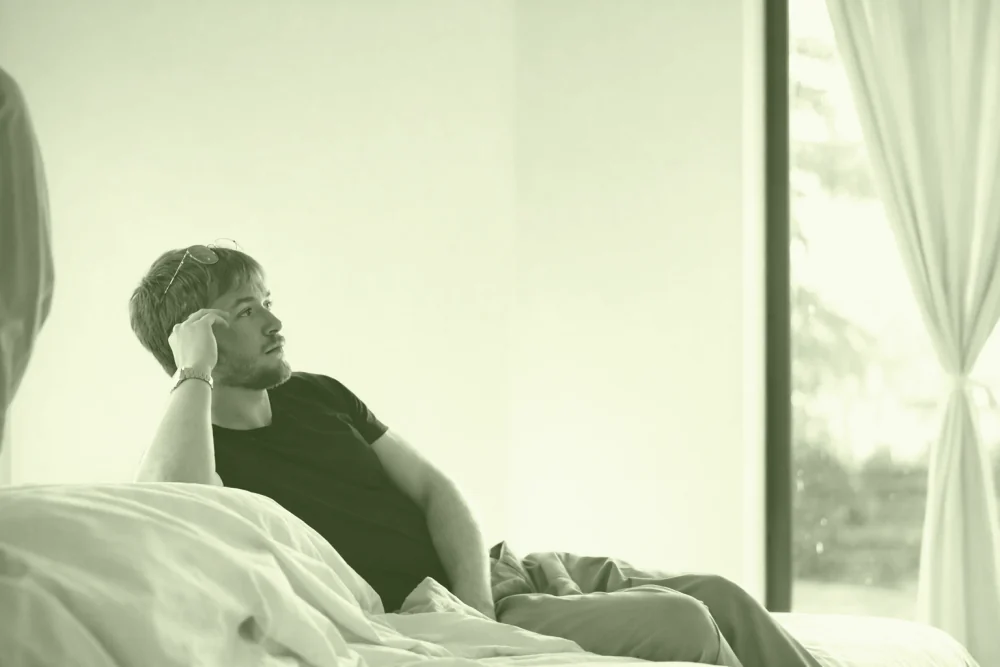 Aodren Le Pesquer, assis sur son lit, le regard tourné vers la fenêtre.